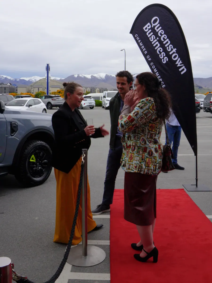 Guests arriving on the red carpet outside Macaulay Motors in Frankton, next to a Queenstown Business flag