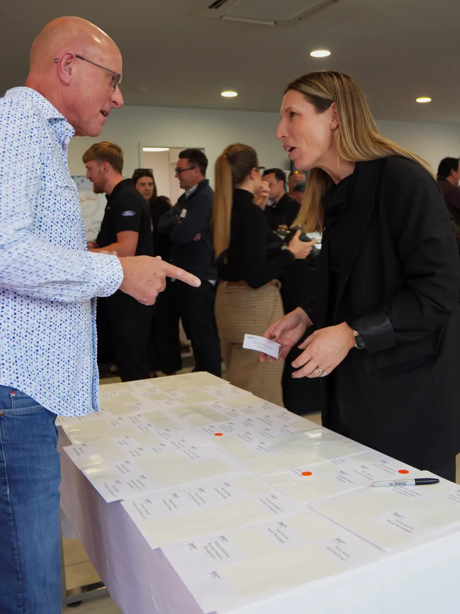 Guests collecting name badges from the welcome table inside the Macaulay Motors showroom