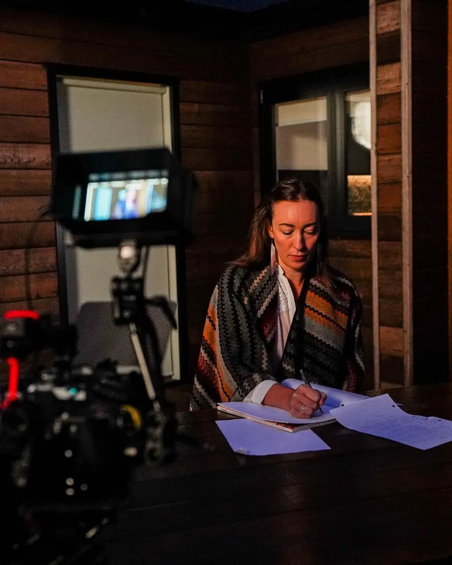 An actor reading a script on the One In Ten set in Glenorchy, with a cinema camera in the foreground