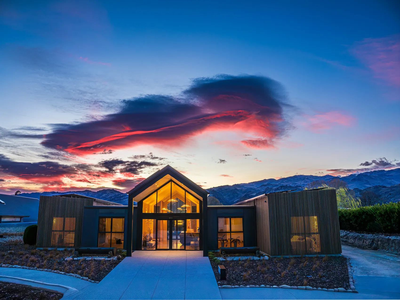 Pure Senses day spa at Mount Pisa near Cromwell, lit from inside at dawn under a red and blue sky